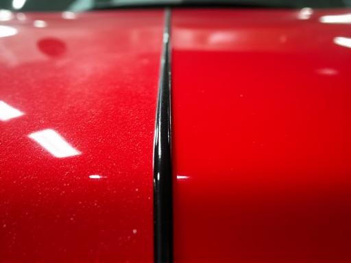 A 50/50 shot showing the difference after paint correction on a red car panel.
